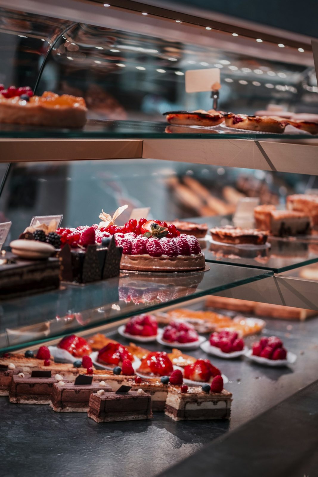 Banco refrigerato con tortine alla frutta e dolci al cioccolato in fila dietro il vetro